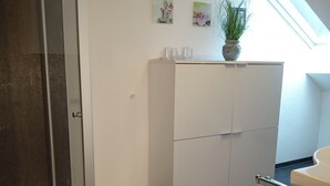 Un baño moderno con ducha, un mueble blanco y un tragaluz.
