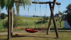 A wooden swing set in a grassy field with a clear sky. - Cozy vacation apartment on the farm - vacation for the whole family (Argenbühl)