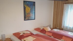 Una cama doble con una colcha estampada, una mesita de noche con una lámpara, y un cuadro en la pared.