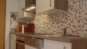 A kitchen with white cabinets, a wooden countertop, a tiled backsplash, and a wall clock. - Cozy vacation apartment on the farm - vacation for the whole family (Argenbühl)