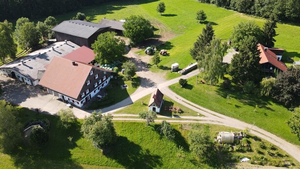 An aerial view of a rural property with a large barn, a farmhouse, and surrounding fields. - Cozy vacation apartment on the farm - vacation for the whole family (Argenbühl)