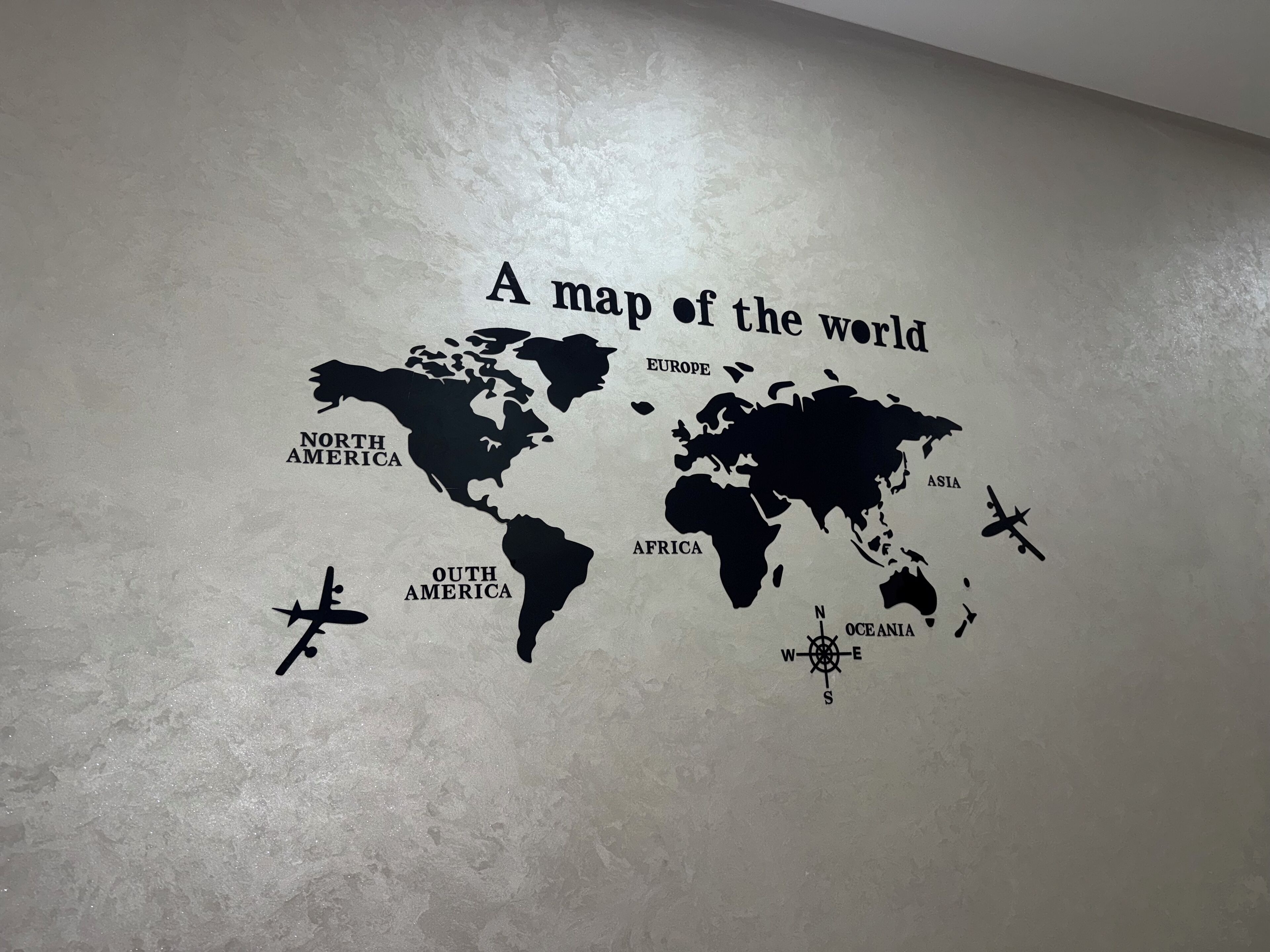 A wall decal of a world map with labeled continents and a compass rose.