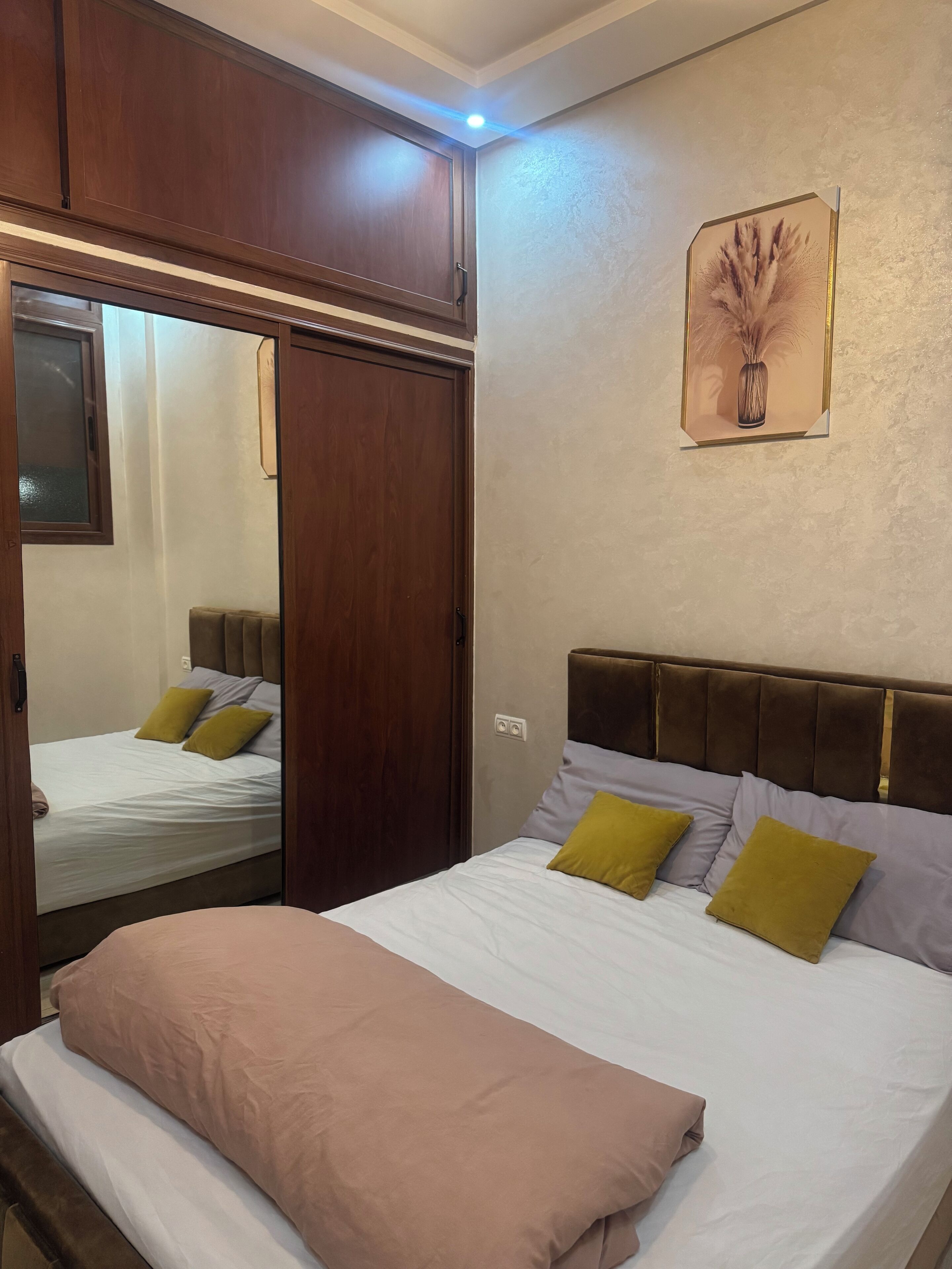 Un dormitorio con cama, armario y espejo.