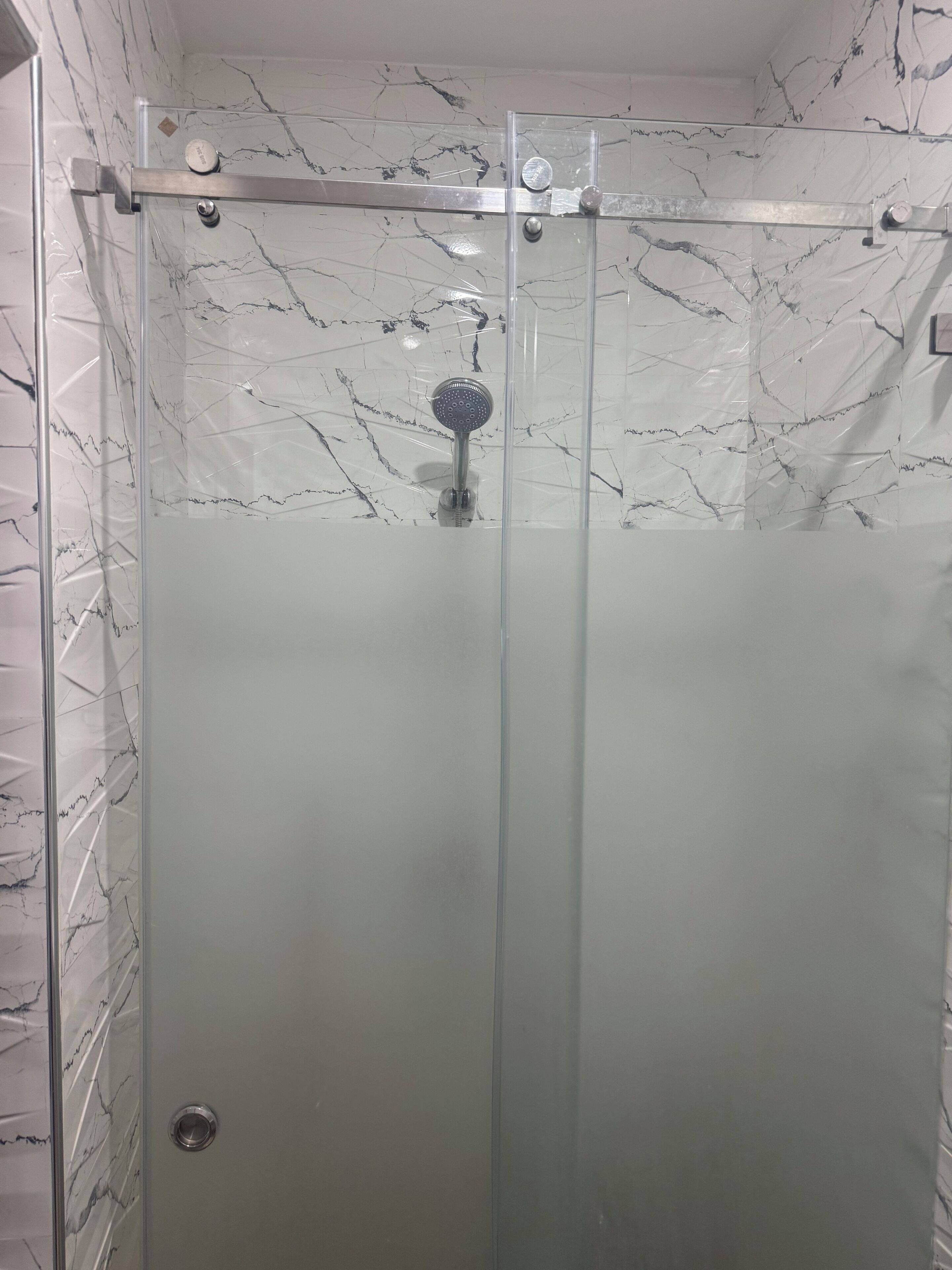 Eine Duschkabine mit Glaswänden, einer Handbrause und einer Bedienkonsole.