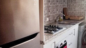 Cucina con frigorifero in acciaio inossidabile, piano cottura a gas, forno a microonde e lavatrice.