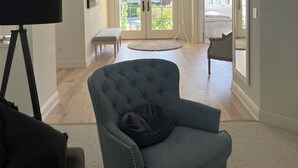 En rummelig stue med en stor lænestol, en bænk og en dør til en balkon.