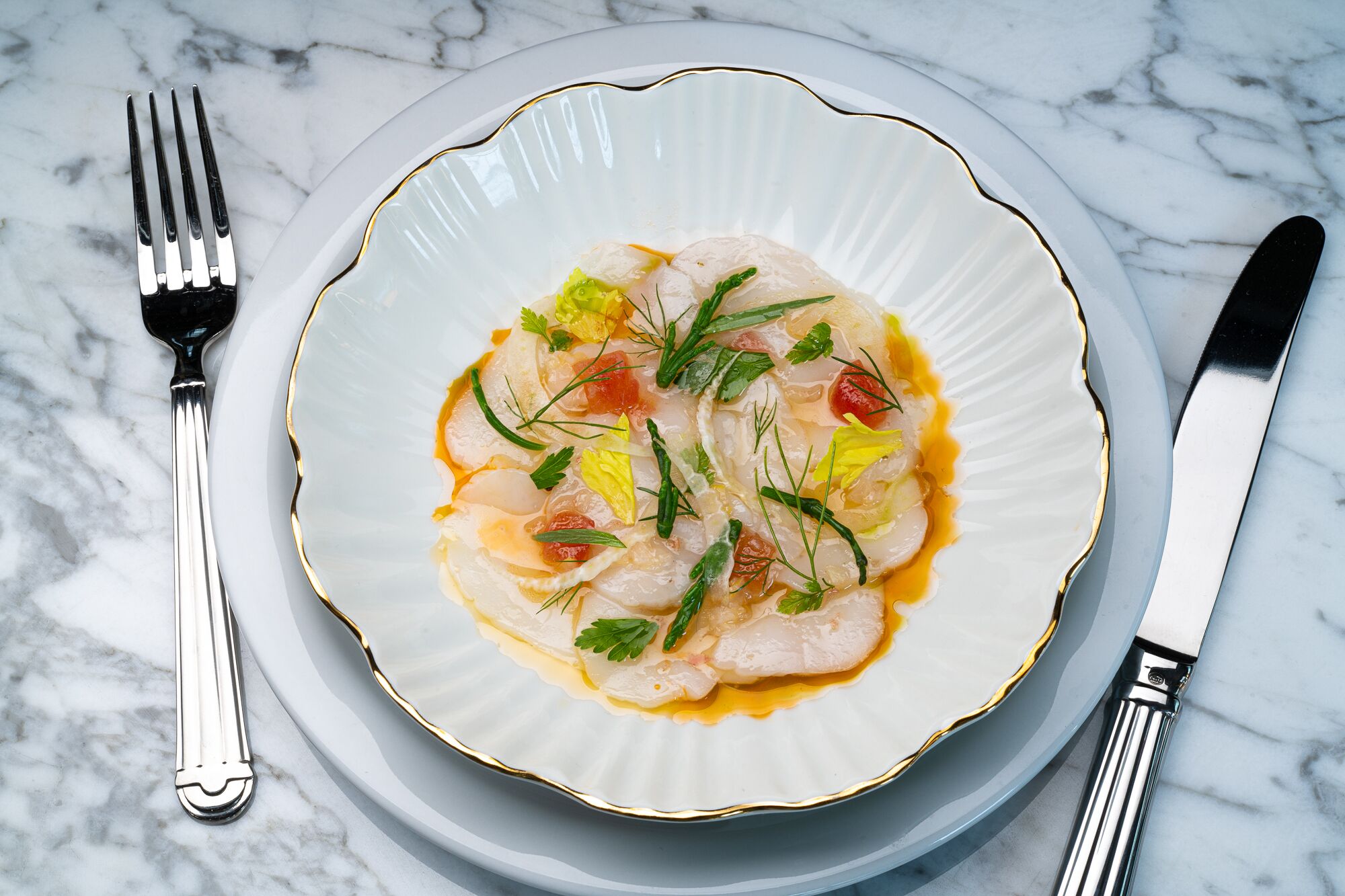 A plate of food with a fork and knife on a marble surface.