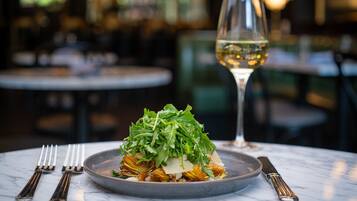 A plate of food with a glass of white wine on a marble table.