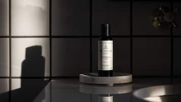 A bottle of Huckleberry Lotion on a reflective surface with a shadow of a person in the background.