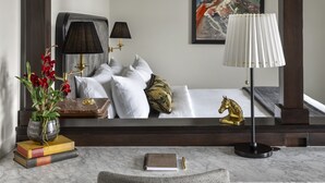A hotel room with a bed, two bedside lamps, a desk with a chair, a vase with flowers, and a framed artwork on the wall. - The Avery Hotel (Boise)
