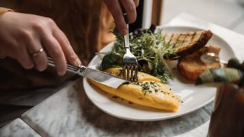 A person cutting an omelette on a plate with a fork.