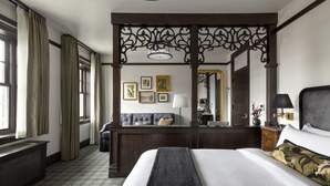 A hotel room with a large bed, a sitting area with a sofa, a desk, and a large mirror. - The Avery Hotel (Boise)
