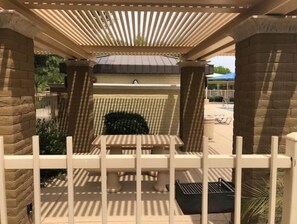 Relax in a serene outdoor seating area with a table and chairs, surrounded by a white fence and stone pillars.