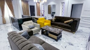 A modern living room with a sofa, armchairs, a coffee table, and a dining area. - Spacious 3 bedroom  Apartment,  All room ensuite , Ipaja Lagos (Lagos)