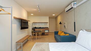 Una habitación de hotel moderna con cama, sofá, escritorio y kitchenette.