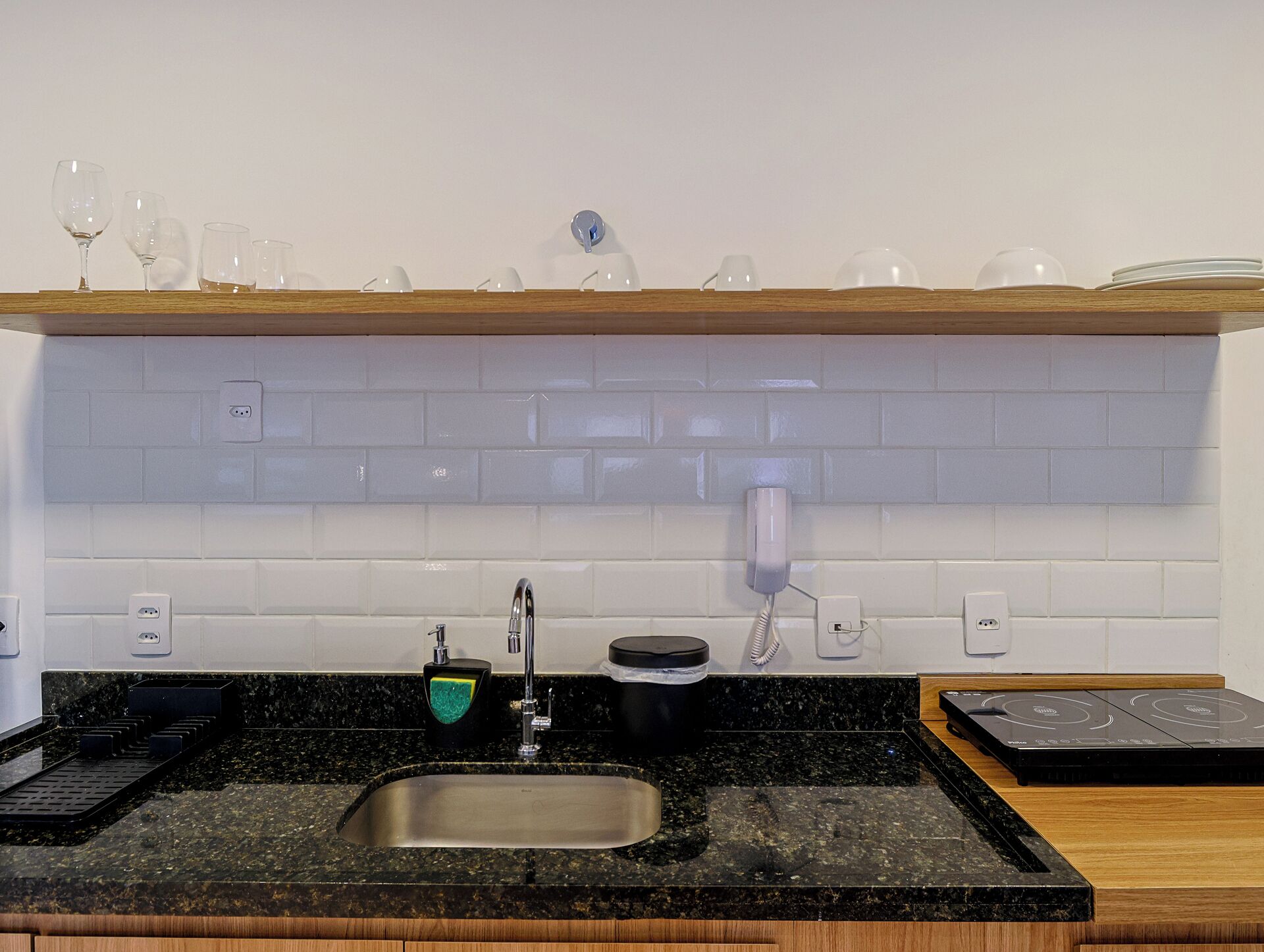 A kitchen with a granite countertop, stainless steel sink, and a built-in oven.
