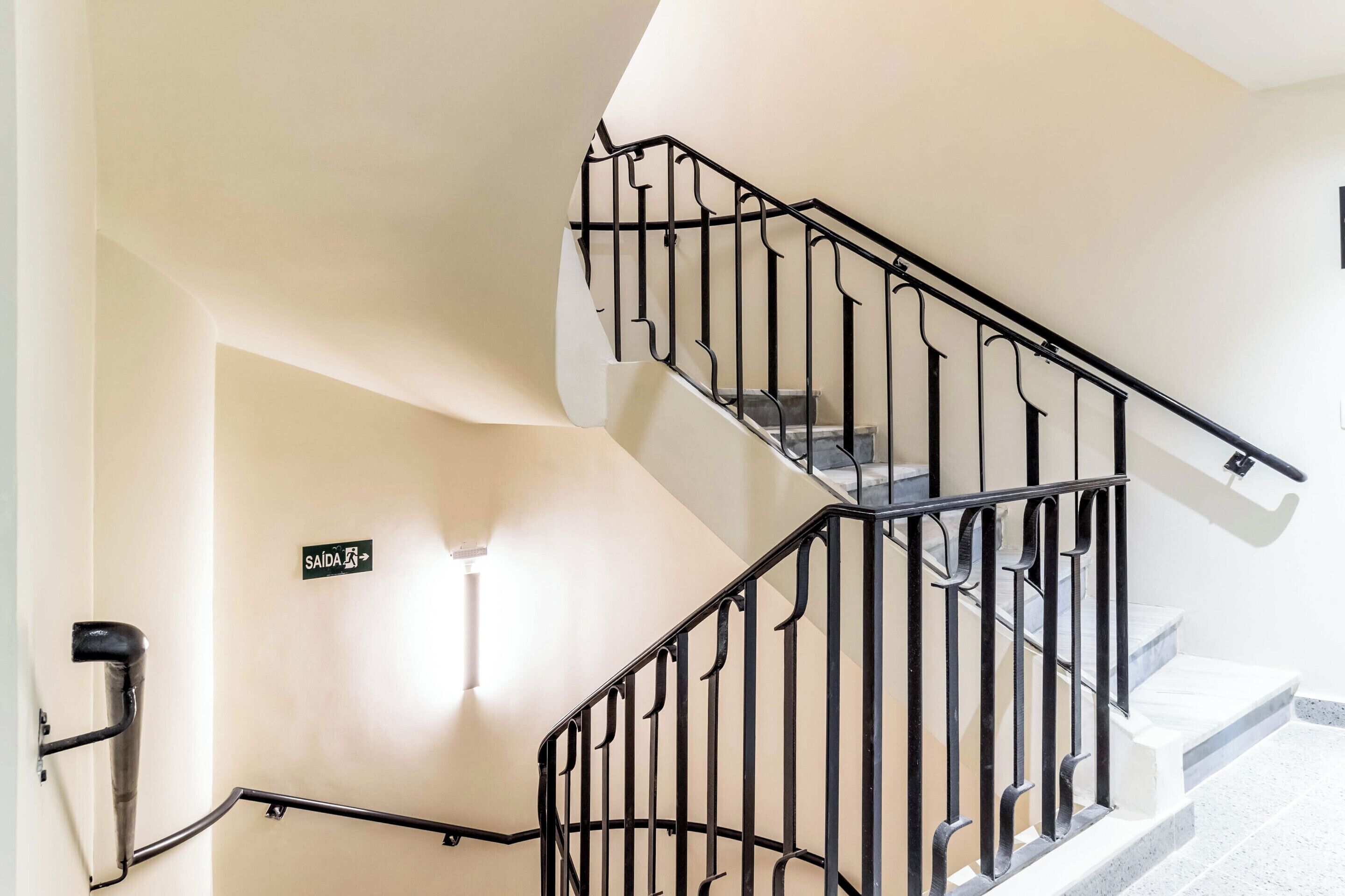 A staircase with black railings and a sign indicating the exit direction.