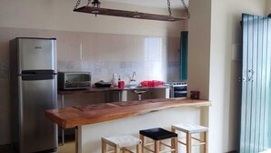 A compact kitchen with a stainless steel refrigerator, a microwave, a stove, and a wooden countertop. - Casa do Renato na Chapada Diamantina (Alto das Pedras Lençóis)