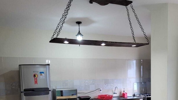 A modern kitchen with a wooden island, stainless steel appliances, and a hanging light fixture. - Casa do Renato na Chapada Diamantina (Alto das Pedras Lençóis)