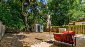 A backyard with a patio area, a small shed, and a wooden fence. - Gainesville Cozy Pet friendly Near UF & Downtown (Gainesville)