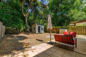 A backyard with a patio area, a small shed, and a wooden fence. - Gainesville Cozy Pet friendly Near UF & Downtown (Gainesville)