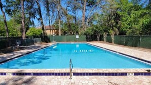 A rectangular swimming pool with a 3 ft depth marking, surrounded by a brick deck and a green fence. - Gainesville Nook Room (Gainesville)