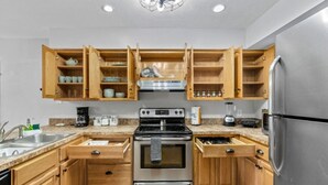 A kitchen with wooden cabinets, stainless steel appliances, and a granite countertop. - Gainesville Nook Room (Gainesville)