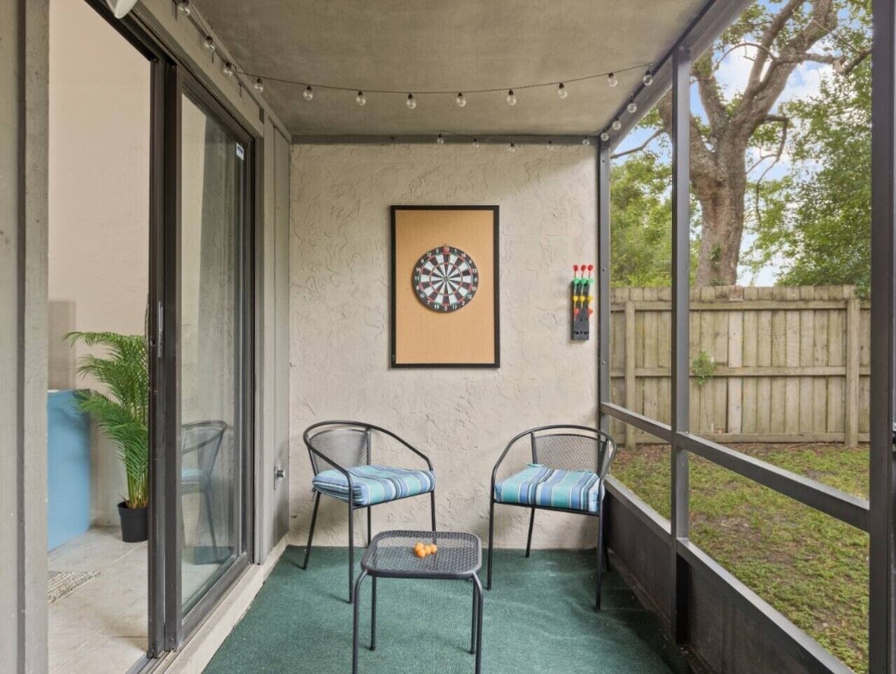 A balcony with two chairs, a dartboard, and a small table with fruit.