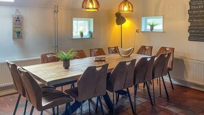 Zona pranzo con tavolo in legno, otto sedie e lampadari a sospensione.