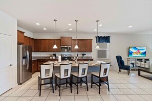 A modern kitchen with wooden cabinets, stainless steel appliances, and pendant lighting. - 8815 Macapa Drive (Kissimmee)