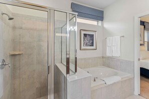 A modern bathroom with a glass shower enclosure, a bathtub, and a framed artwork on the wall. - 8815 Macapa Drive (Kissimmee)