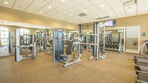 A gym with various exercise machines, a mirrored wall, and a television screen. - 8815 Macapa Drive (Kissimmee)