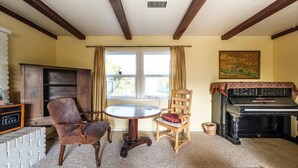 A living room with a piano, two chairs, a table, a fireplace, and a window with curtains. - Starfish -Trinidad Ocean Ave - Couples Haven (Trinidad)