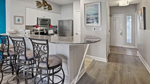 A modern kitchen with white cabinets, stainless steel appliances, and a central island with bar stools.