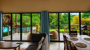 A spacious living area with a large sliding glass door leading to a pool and garden. - Modern villa with stunning jungle views (Provincia de Puntarenas)