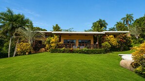 A modern two-story house with a well-maintained lawn and tropical landscaping. - Modern villa with stunning jungle views (Provincia de Puntarenas)