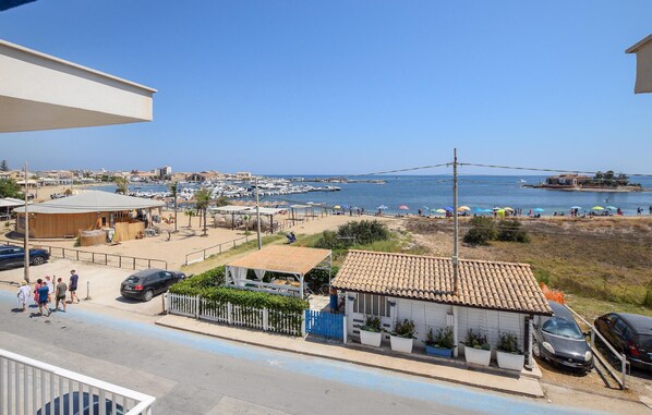 A coastal view with a marina, beach umbrellas, and a small building with a tiled roof.