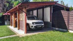 Un VUS blanc est garé dans un garage fermé, dont le toit et les murs sont en bois.