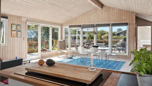Una habitación con paneles de madera y un amplio ventanal corredera que da a un patio al aire libre.