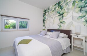 A bedroom with a bed, a nightstand, a lamp, and a window with a view of greenery. - Gorgeous apartment in Cavtat (Cavtat)