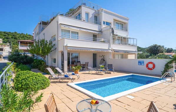 A two-story building with a swimming pool, outdoor seating, and a lifebuoy on the wall. - Gorgeous apartment in Cavtat (Cavtat)