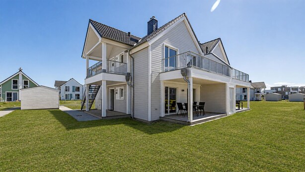 A two-story house with a balcony, a garage, and a covered patio area. - Ferienwohnung Meerzeit (Kappeln)