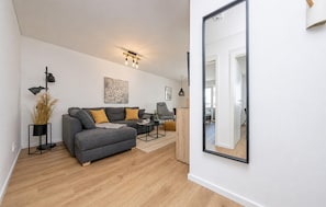 Un salon moderne avec un canapé gris, une table basse et un grand miroir.