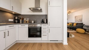 A modern kitchen with white cabinets, a Bosch oven, and a stainless steel range hood. - Ferienwohnung Meerzeit (Kappeln)