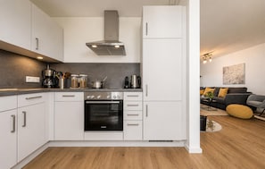 Une cuisine moderne avec des armoires blanches, un four Bosch et une hotte de cuisiniĂšre en acier inoxydable.