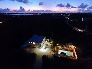 Un edificio grande de dos pisos con piscina e iluminación exterior.