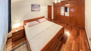 A bedroom with a large bed, wooden wardrobe, and a nightstand. - Cozy apartment in Kukci with swimming pool (Kukci)