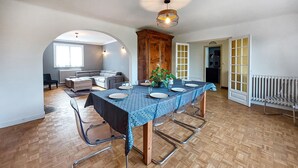 Un coin repas avec une table dressée pour six personnes, un buffet en bois et un radiateur.