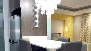 Una cocina moderna con un refrigerador empotrado, una mesa de comedor con cuatro sillas y una lámpara original sobre la mesa.