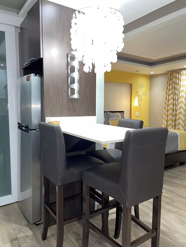 A modern kitchen with a built-in refrigerator, a dining table with four chairs, and a unique light fixture above the table.